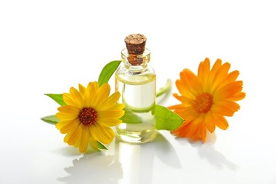 An image of some flowers next to a glass vile which contains an essential oil that is good for mood boosting. 